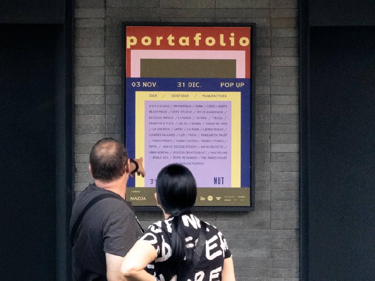 Personas mirando el afiche de la feria Portafolio